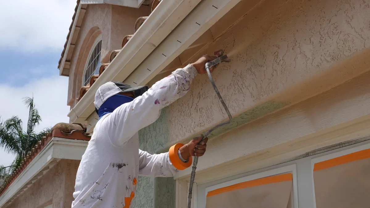 Expert stucco contractors Northbrook using a special spray to paint the house